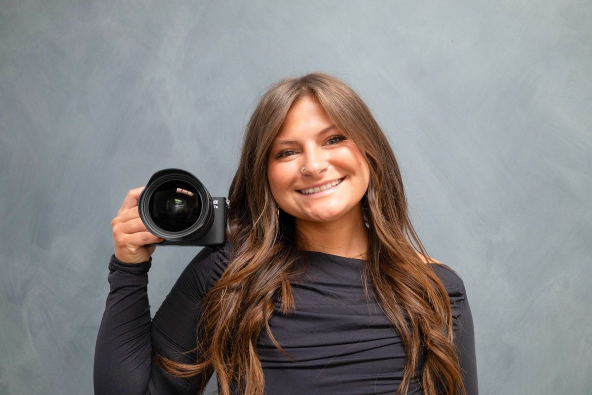 Morgan holding a camera and smiling