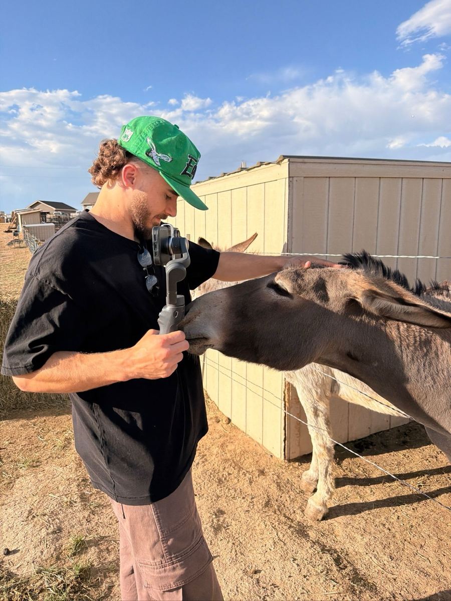Andrew filming with a gimbal while petting a donkey