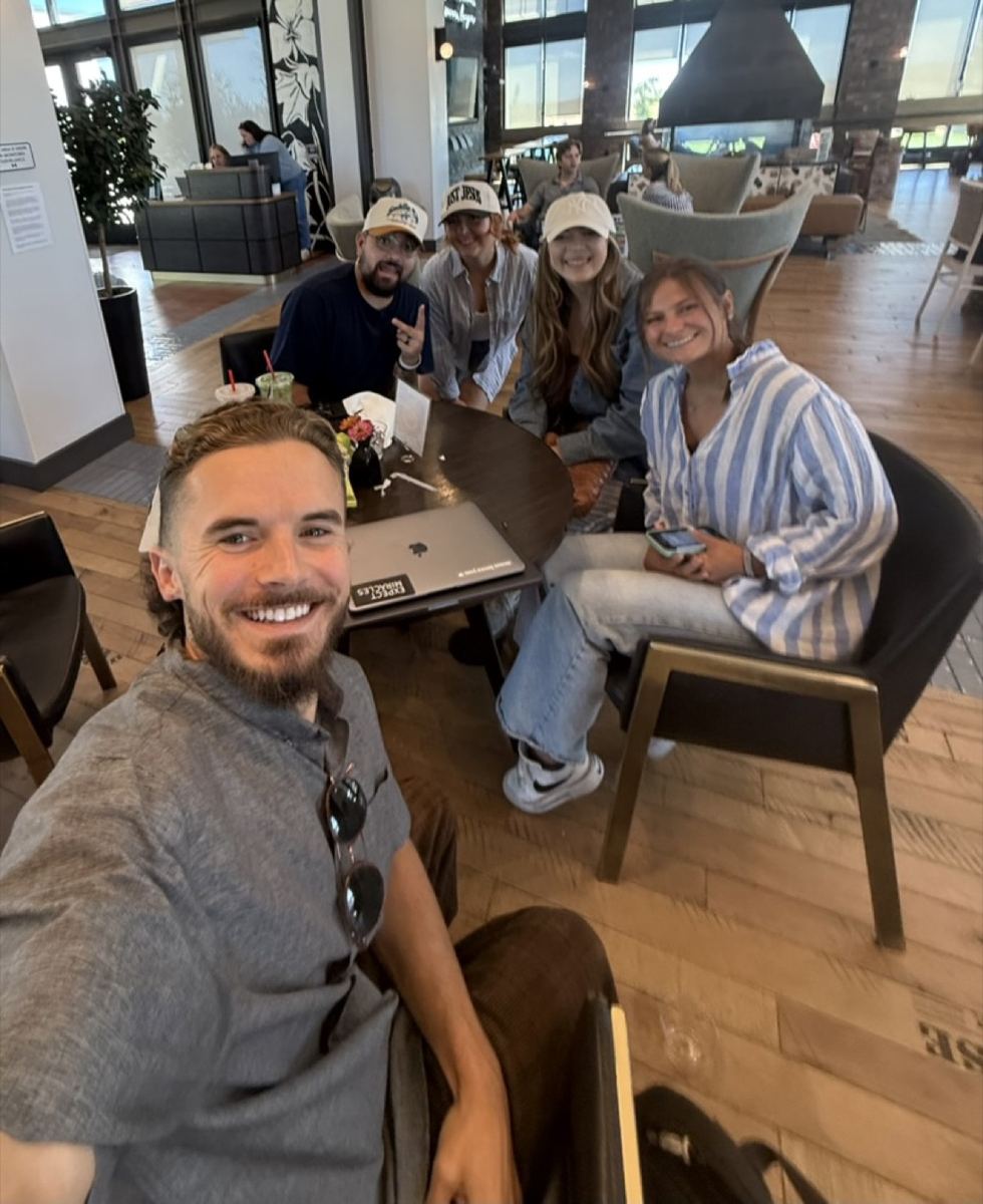 Andrew with the team around a table with a laptop